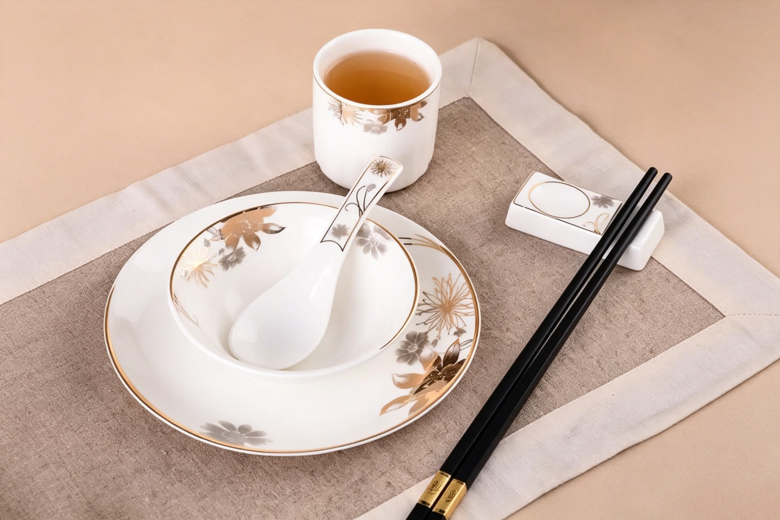 A proper Chinese table setting with chopsticks placed horizontally across a small rest, a soup spoon, and a tea cup