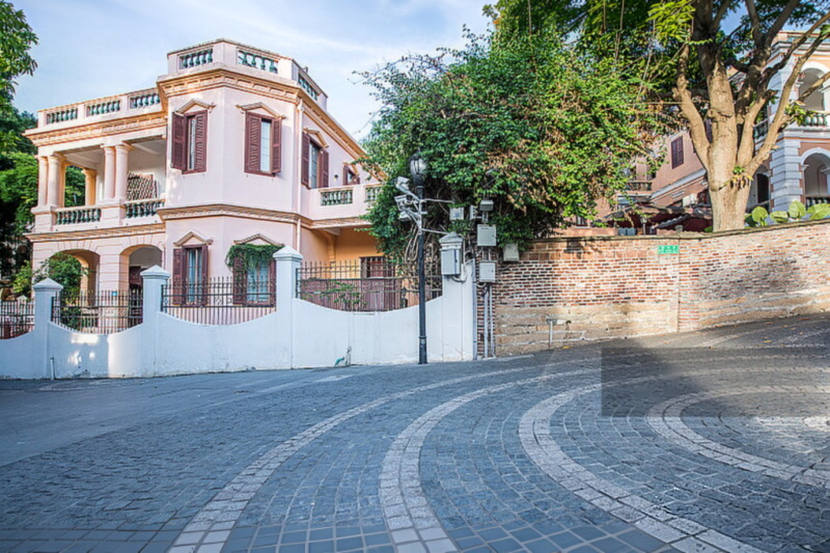 A colonial-era villa on Gulangyu Island — red brick and stone, shaded by banyan trees, bougainvillea spilling over the wall